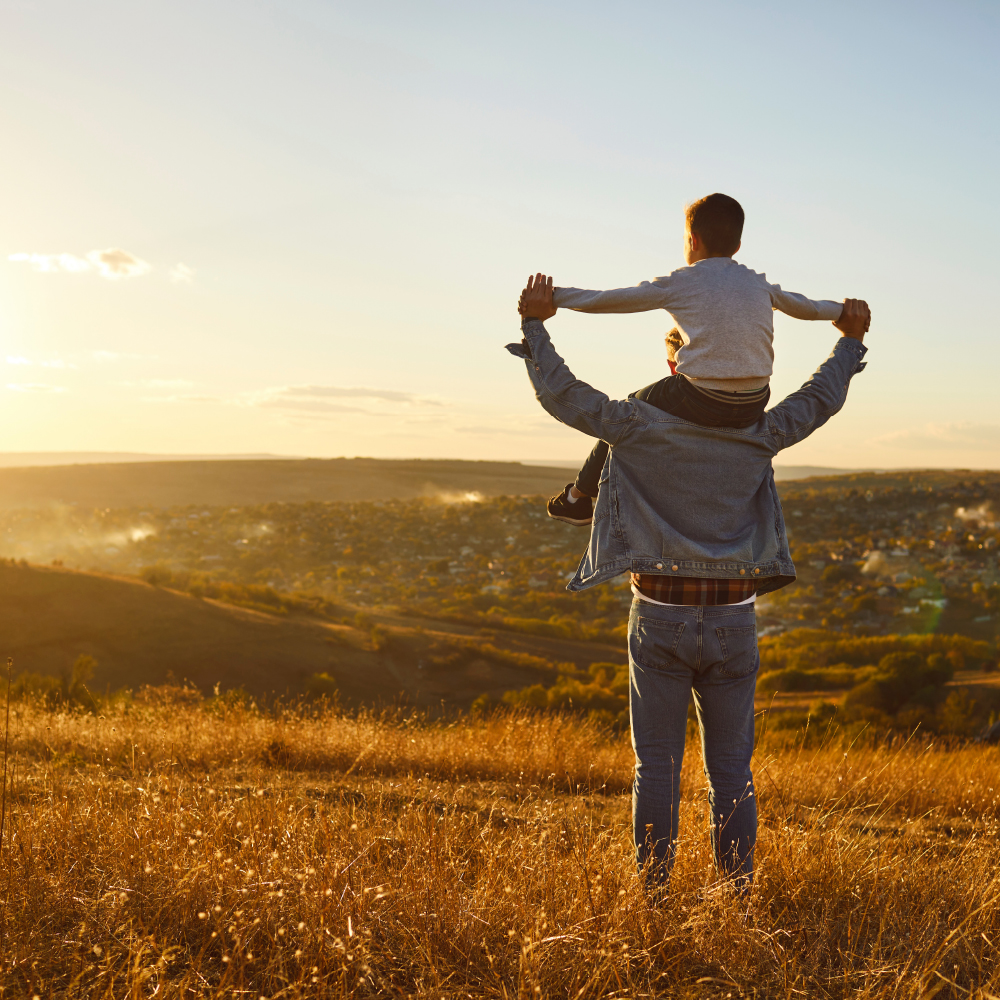 A father carrying his child at sunset